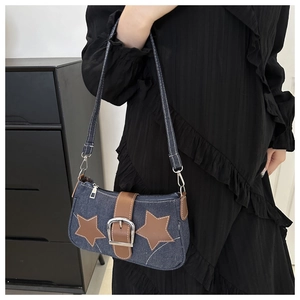 Detail van vintage denim baguette tas met bruine lederen sterren en zilveren gesp