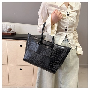 Close-up of black crocodile pattern tote bag showing glossy texture and dual handles
