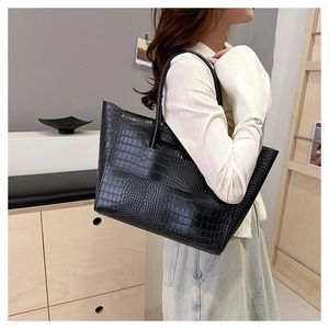Detail of black crocodile embossed tote bag texture with double straps shown on model