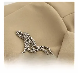 Detailed macro shot of silver metal chain strap on khaki textured fabric background