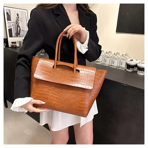 Close-up of the brown crocodile texture and handle detail on a large tote bag