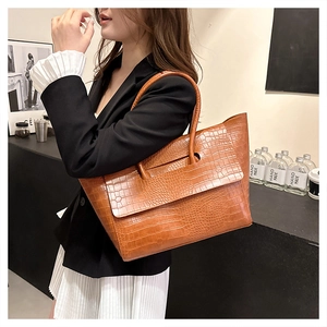 Brown crocodile pattern tote bag with double handles shown on a stylish model