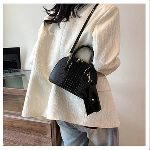 Detail of black crocodile pattern shell bag with metal zipper and mini pouch on strap