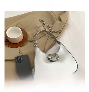 Detail of silver metallic crescent bag with bow buckle, chain strap and top handle