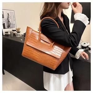 Detail view of large brown crocodile embossed leather tote bag for office and commute