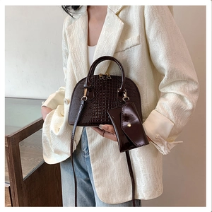 Detail of crocodile embossed shell bag in dark brown with matching envelope pouch