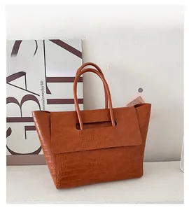 Detailed view of crocodile embossed leather texture on a vintage brown tote bag