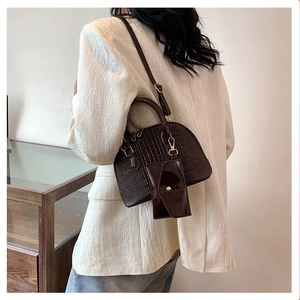 Detail view of dark brown crocodile pattern shell bag worn as a crossbody on a model