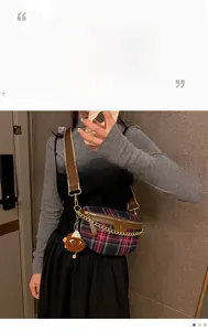 Detail of plaid crossbody bag featuring gold chain strap and brown leather trim accents