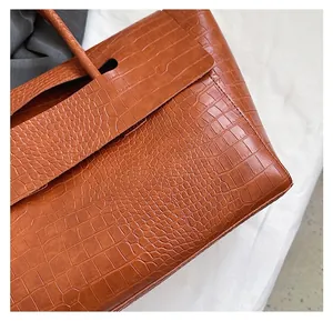 Detail of premium brown crocodile pattern leather texture and stitching on the tote bag