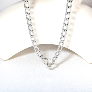 Close-up of a silver cuban chain necklace with a lobster clasp on a white minimalist display