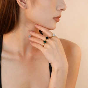 Detail of three 18K gold plated rings set with emerald, black, and clear round gemstones