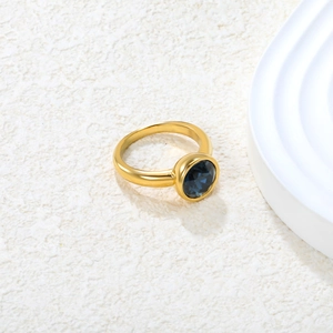 18k gold plated stainless steel ring with oval dark blue gemstone on white textured background