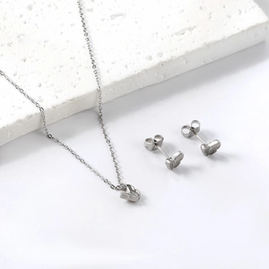 Macro shot of silver butterfly jewelry set including necklace and stud earrings on stone