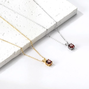 Detail of red round zircon pendants in gold and silver claw settings on white stone