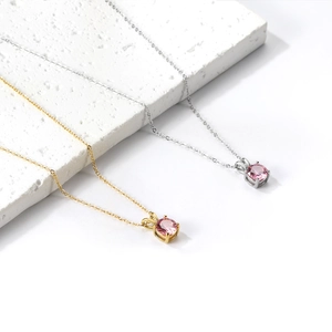 Close-up of pink round-cut gemstone pendants with bunny ear charms on fine gold and silver chains