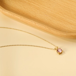 Close-up of gold chain necklace featuring a four-prong set pink round zircon pendant