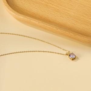 Detail of bunny ear gold necklace with a round lavender crystal on warm background