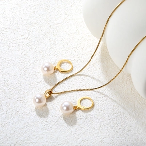 Elegante set di collana e orecchini di perle dorate su uno sfondo bianco strutturato