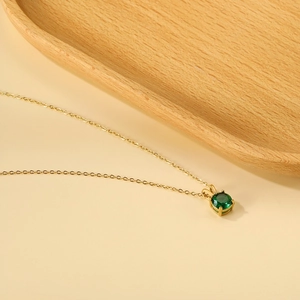 Detail view of the green round gemstone pendant with rabbit ear bail on gold chain
