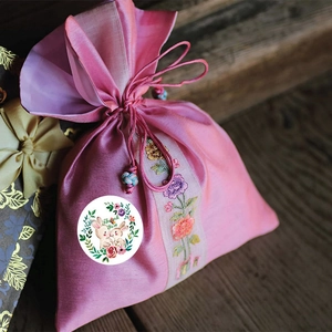 Pink satin drawstring gift bag with floral embroidery and Thank You rabbit sticker