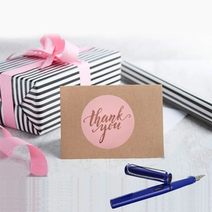 Pink thank you sealing labels with rose gold lettering on a kraft card and gift box