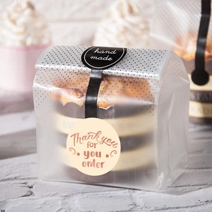 Faded pink frosted bakery bags with gold Thank You For Your Order stickers on wood background