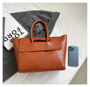 Detail view of large brown crocodile embossed leather tote bag showing spacious capacity