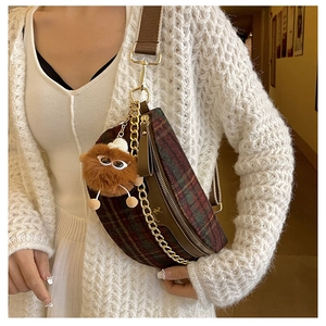 Detail of vintage plaid crossbody chest bag with gold chain and plush monster charm