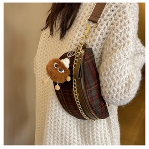 Detail of crossbody bag with vintage plaid pattern, golden chain and plush monster charm