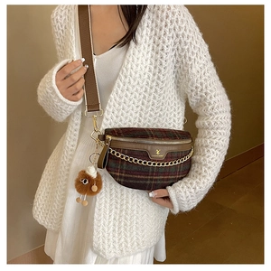 Detail of plaid crossbody chest bag with gold chain and brown plush toy charm