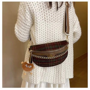 Detail of checkered plaid crossbody bag with gold chain and plush monster charm