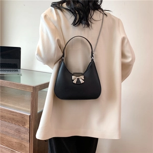 Minimalist black half-moon shoulder bag with silver bow accent and metal chain strap