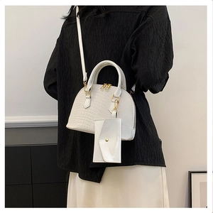 Detailed view of white crocodile pattern shell bag with adjustable strap worn by model