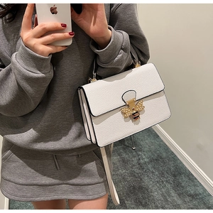 Detailansicht einer weißen Ledertasche mit goldener Perlen-Bienenschließe und Handgriff
