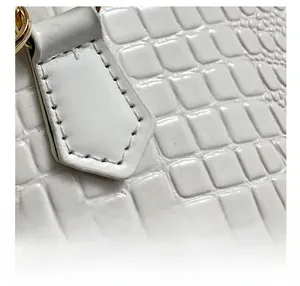 Close-up of white crocodile pattern leather texture with fine stitching and metal hardware