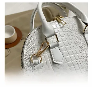 Close-up of golden hardware and white crocodile pattern texture on a shell bag