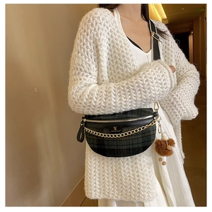 Detail of checkered plaid belt bag with gold chain and plush ball on a knit cardigan