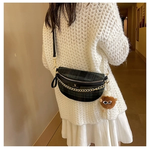 Detail of checkered crossbody chest bag with gold chain and plush monster charm