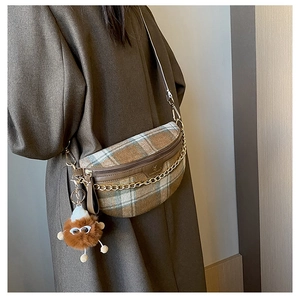 Detail showing vintage plaid crossbody bag with gold chain and cute brown plush charm