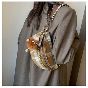 Detail of checkered crescent belt bag with gold chain and plush charm on model