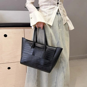 Classic black crocodile pattern tote bag with dual handles in a minimalist interior