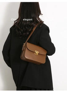 Sac bandoulière en cuir marron avec boucle dorée sur mannequin en blazer noir