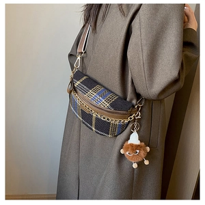 Detail of tweed crossbody bag with golden chain and plush charm on brown strap