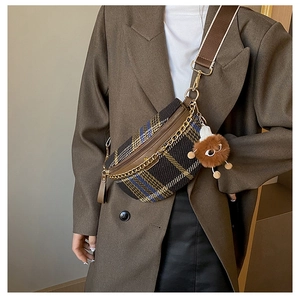 Detail of retro plaid chest bag with golden chain and plush monster charm decoration