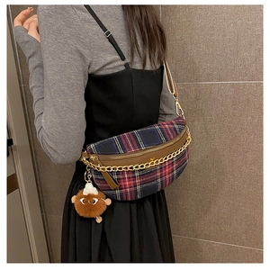Close-up of tartan plaid chest bag with leather trim and decorative gold chain