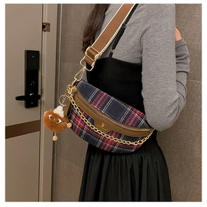 Detail view of plaid crossbody bag featuring gold chain design and fuzzy ball accessory