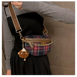 Detail of red and blue plaid crossbody bag with gold chain and plush animal charm