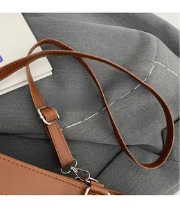 Detail of adjustable brown leather shoulder strap with silver metallic buckle on a handbag