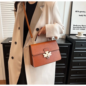 Detailaufnahme der orangebraunen Litschi-Struktur-Tasche mit perlenbesetzter Bienenschließe